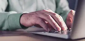 Mains d'un homme tapant sur le clavier de son écran